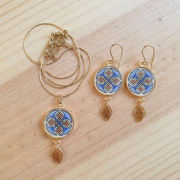 Halsbands h&auml;ngen belyst med bl&aring; palmetter, guld och r&ouml;da fl&auml;tningar p&aring; guldkedja.