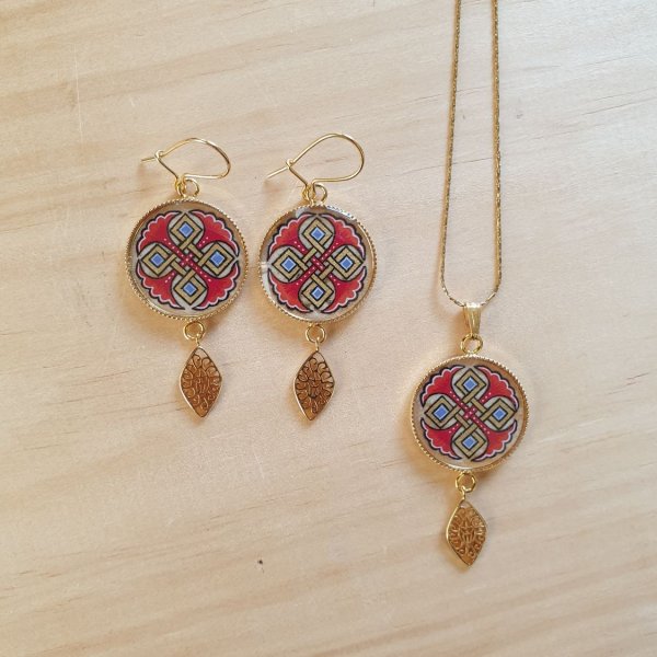 Halsbands h&auml;ngen belyst med bl&aring; palmetter, guld och r&ouml;da fl&auml;tningar p&aring; guldkedja.