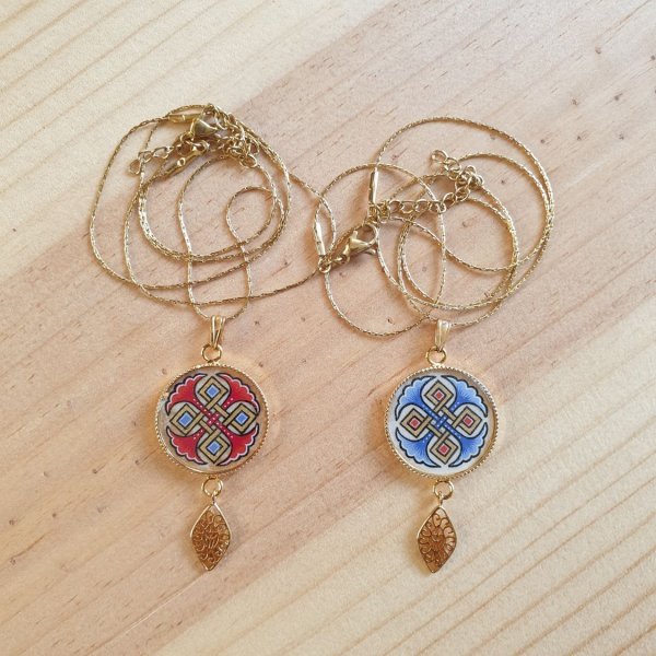 Halsbands h&auml;ngen belyst med bl&aring; palmetter, guld och r&ouml;da fl&auml;tningar p&aring; guldkedja.