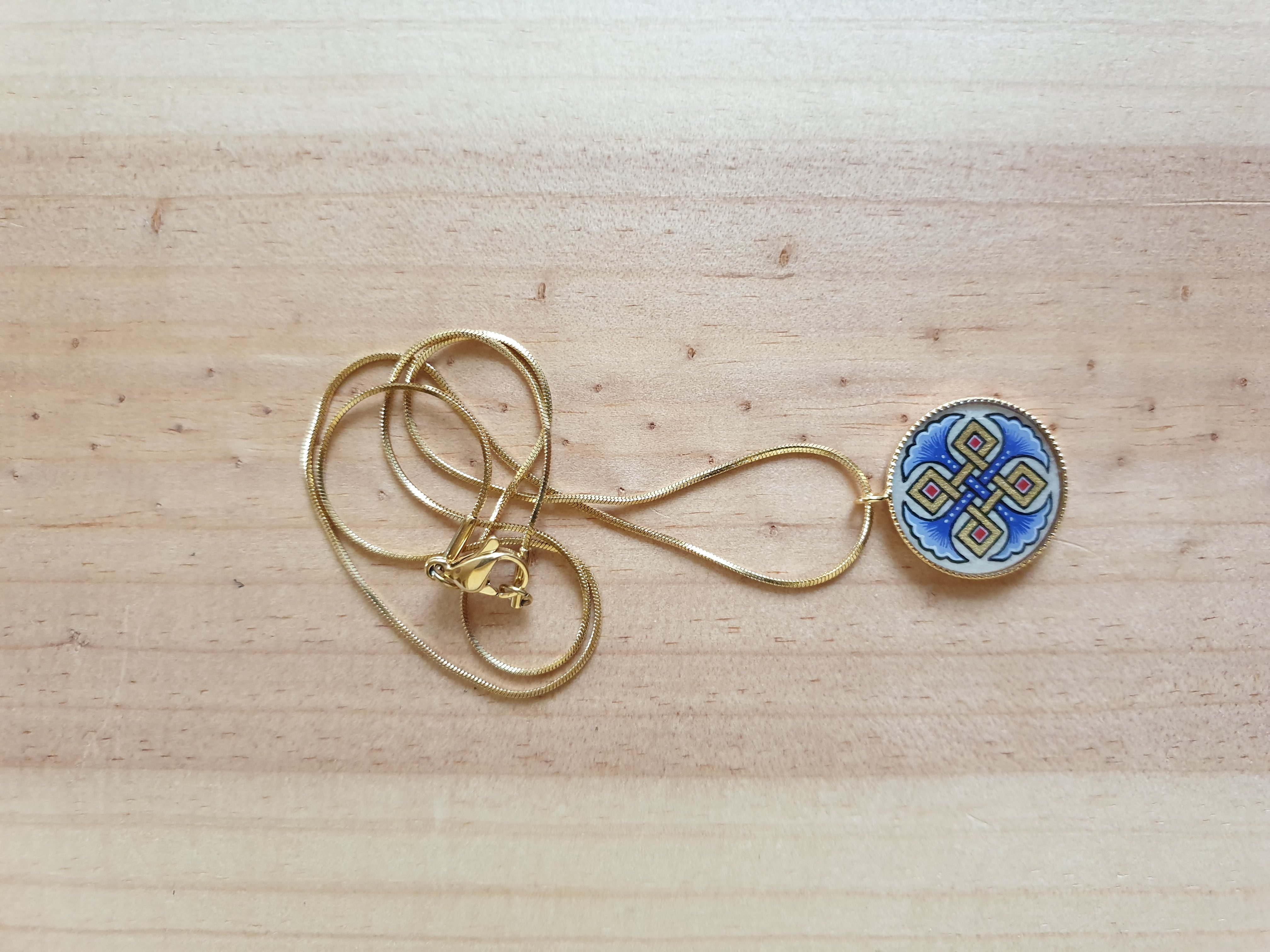 Halsband med hängande halsband med blå palmetter, guld och röda flätningar på guldkedja.