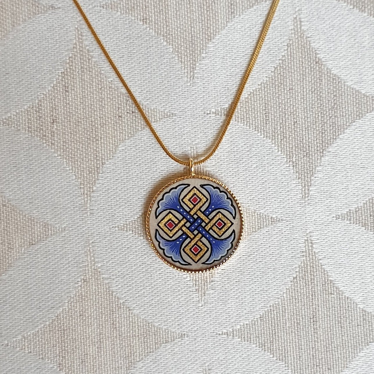 Halsband med hängande halsband med blå palmetter, guld och röda flätningar på guldkedja.