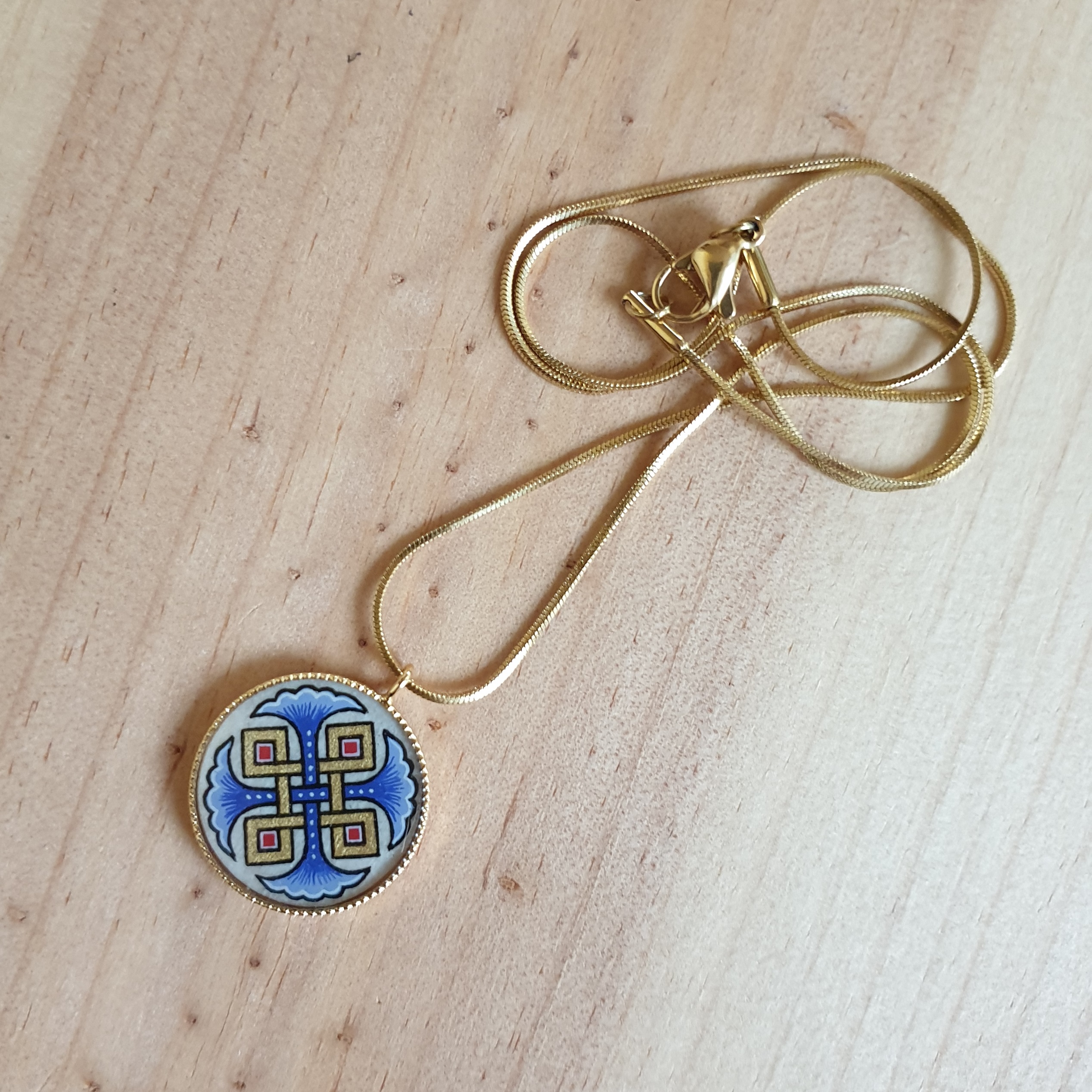 Halsband med hängande halsband med blå palmetter, guld och röda flätningar på guldkedja.