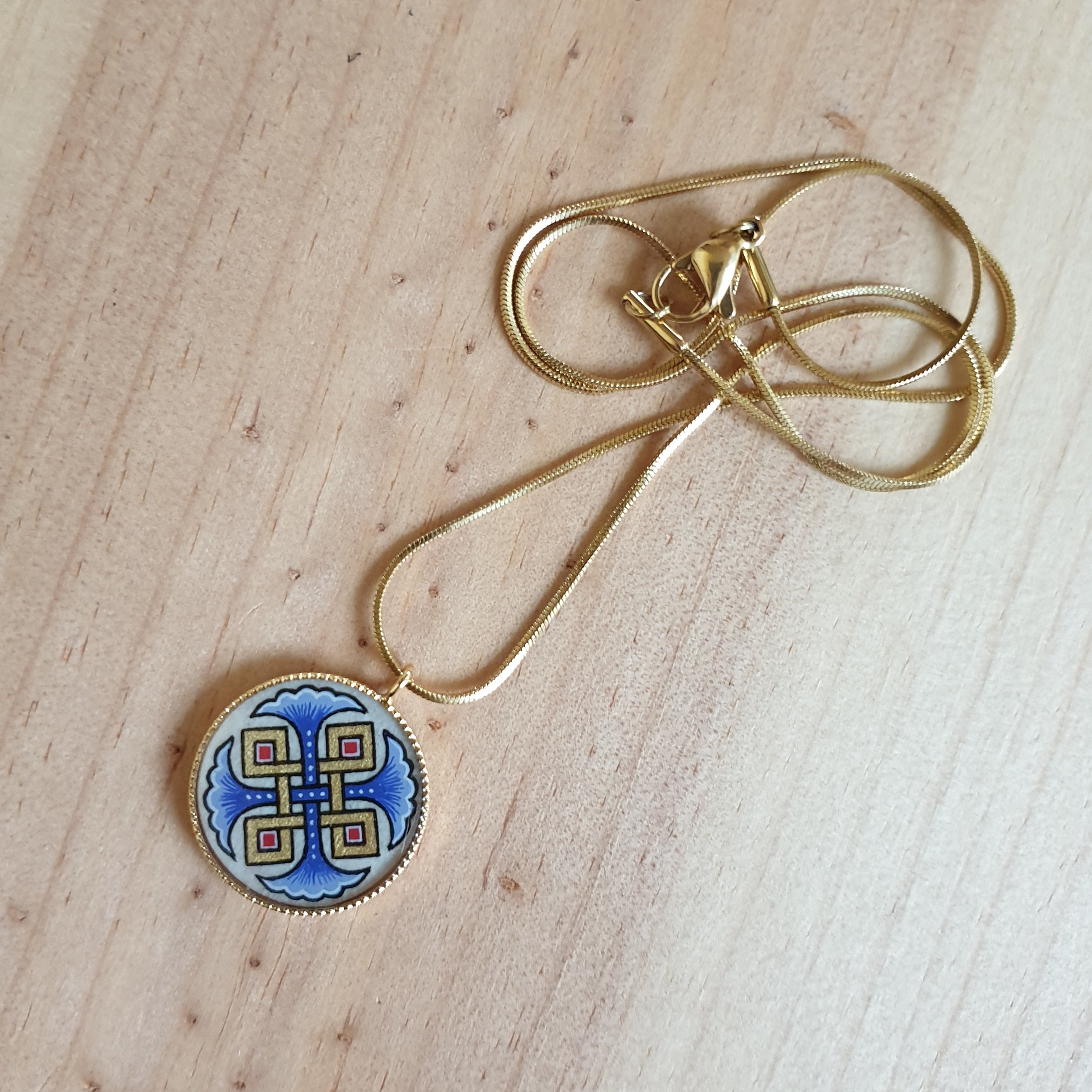 Halsband med hängande halsband med blå palmetter, guld och röda flätningar på guldkedja.