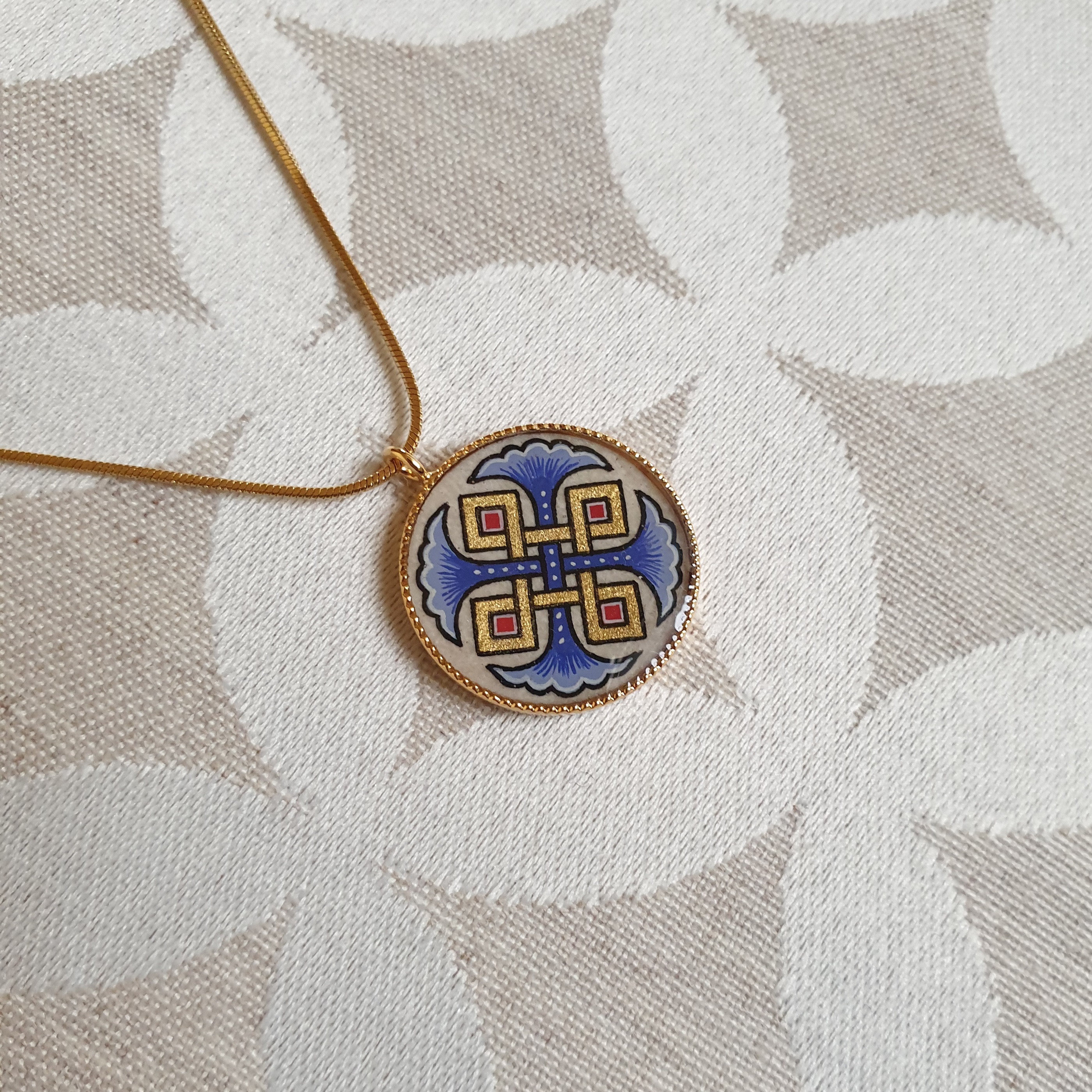 Halsband med hängande halsband med blå palmetter, guld och röda flätningar på guldkedja.