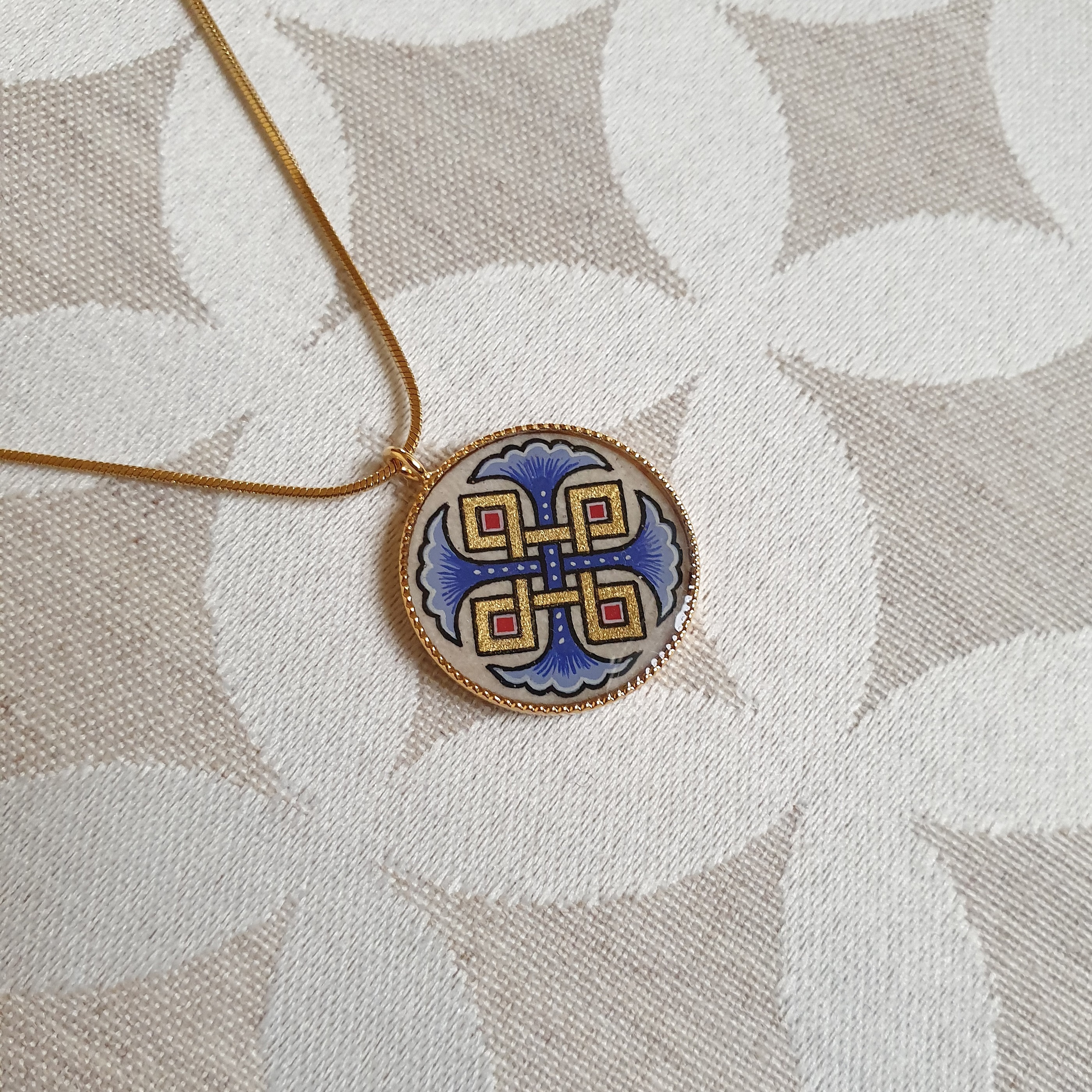 Halsband med h&auml;ngande halsband med bl&aring; palmetter, guld och r&ouml;da fl&auml;tningar p&aring; guldkedja.