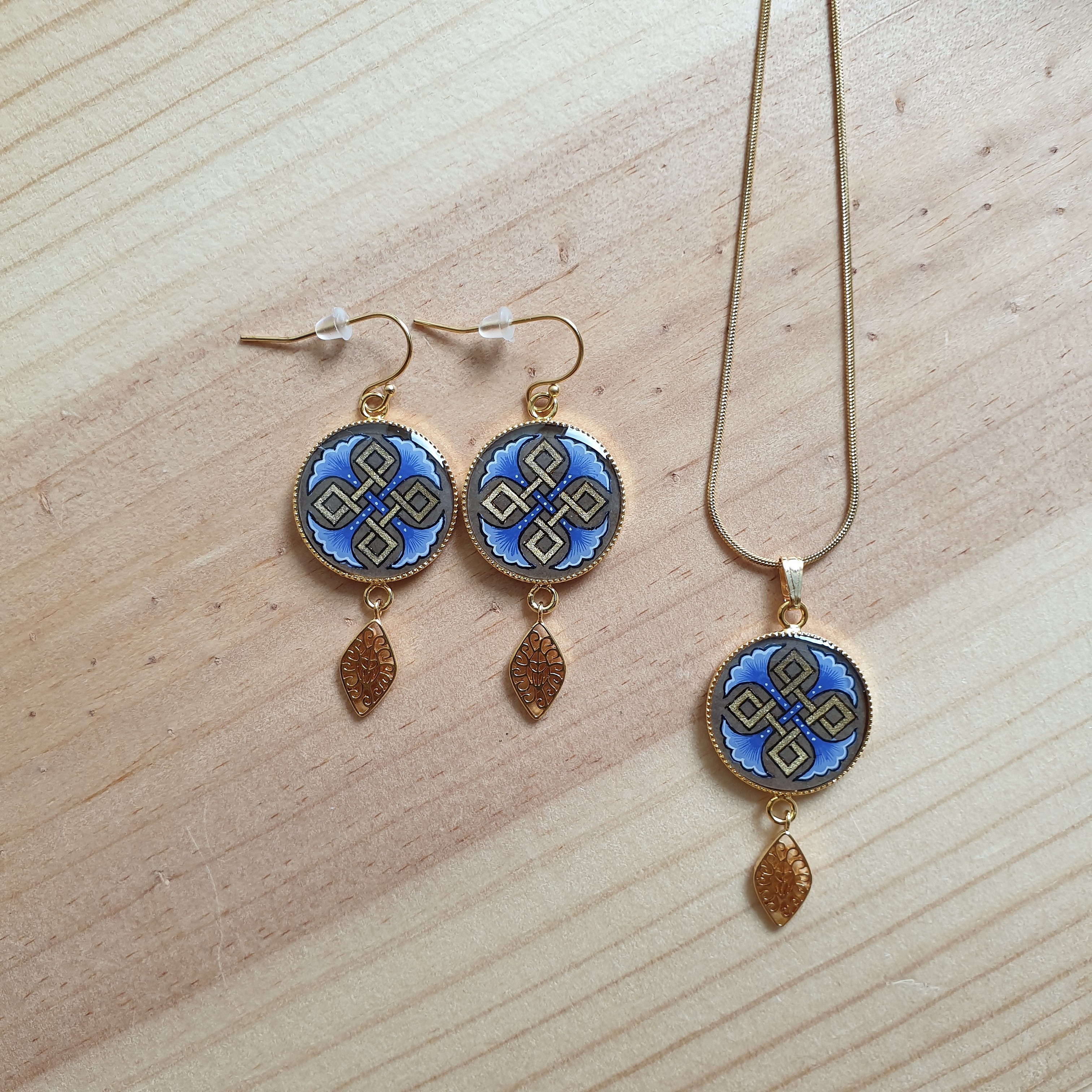 Parure collier et boucles d'oreilles dorées à motifs palmettes bleues.