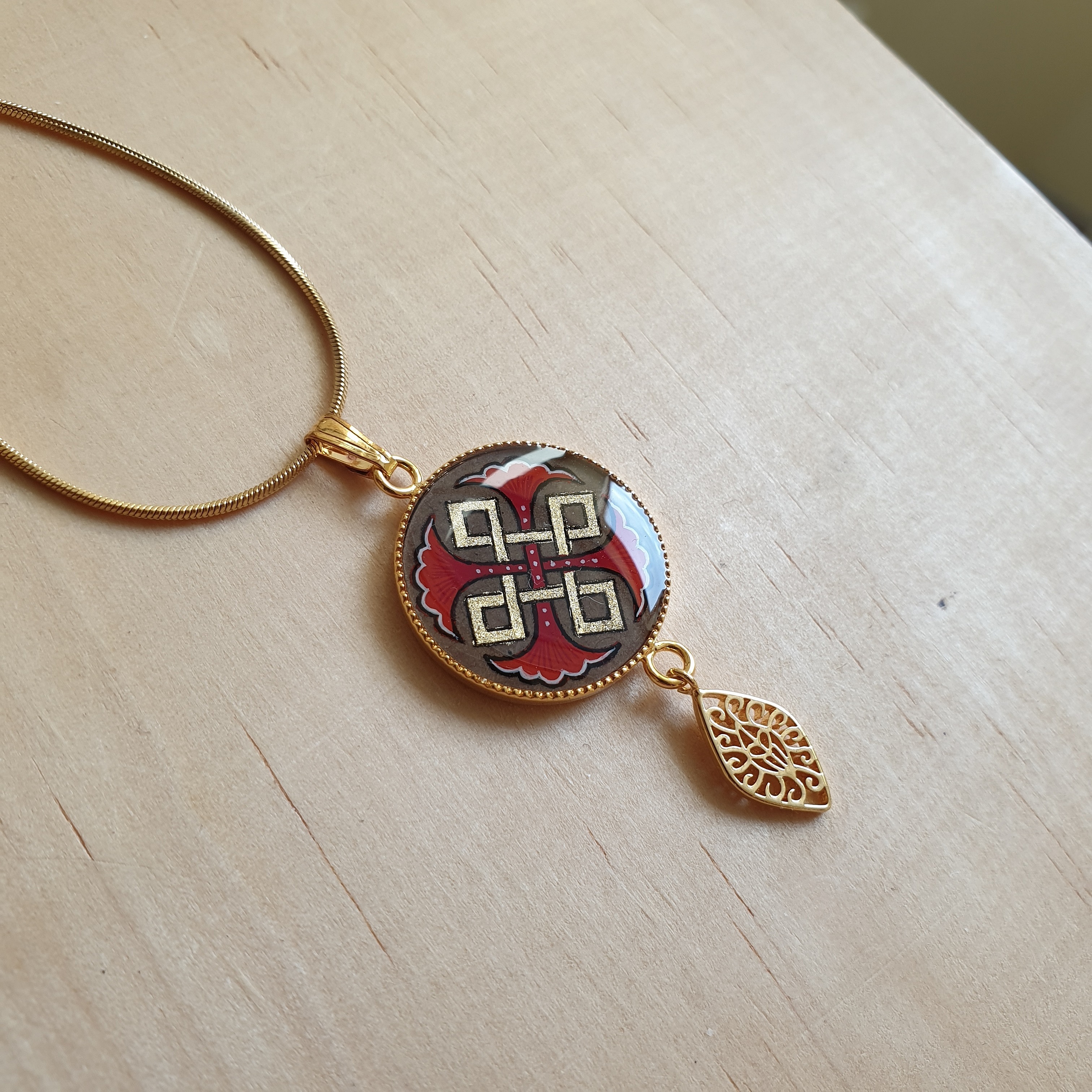 Collier pendentif médaillon enluminé avec palmettes et entrelacs dorés.