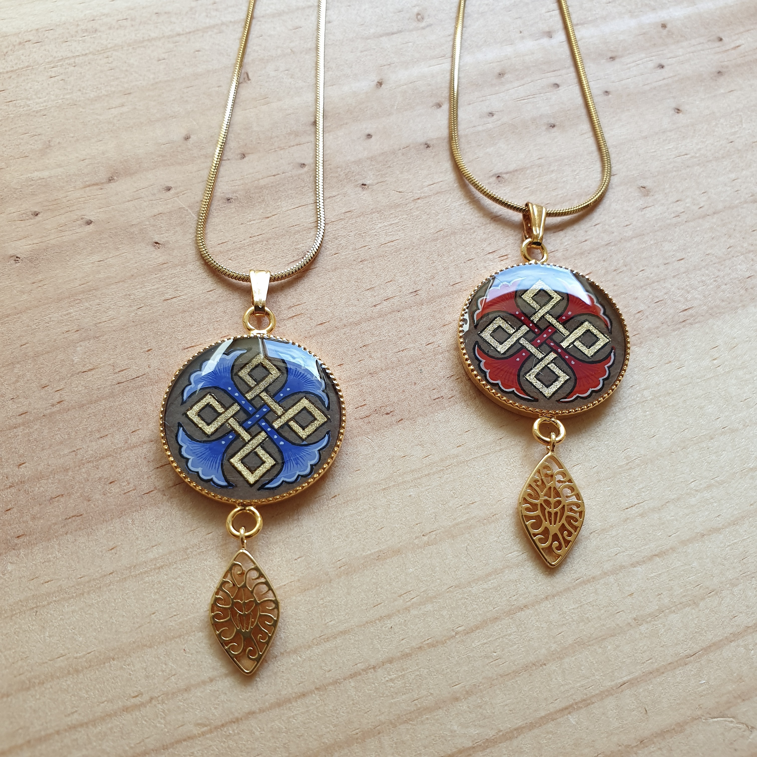Colliers pendentifs dorés avec motifs palmettes et entrelacs colorés.