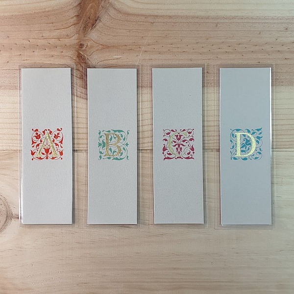 Marque-pages personnalisés avec initiales enluminées et arabesques dorées.